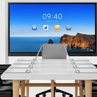 Innotech Conference Room Setup with a Long White Table, Black Chairs, and a Large Screen at the End Displaying a Seaside Wallpaper and Icons.