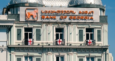 Innotech Historic Bank Building with a Domed Roof, an Orange 'bank of Georgia' Sign, and Georgian Flags Hanging in the Windows.