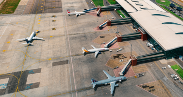 Innotech Aerial View of an Airport Apron with Several Passenger Jets Parked at Gates and Boarding Bridges.